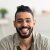 portrait-of-handsome-young-arab-man-smiling-and-looking-at-camera-sitting-on-sofa-at-home-e1687402178567-300x300