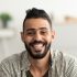 portrait-of-handsome-young-arab-man-smiling-and-looking-at-camera-sitting-on-sofa-at-home-e1687402178567-300x300